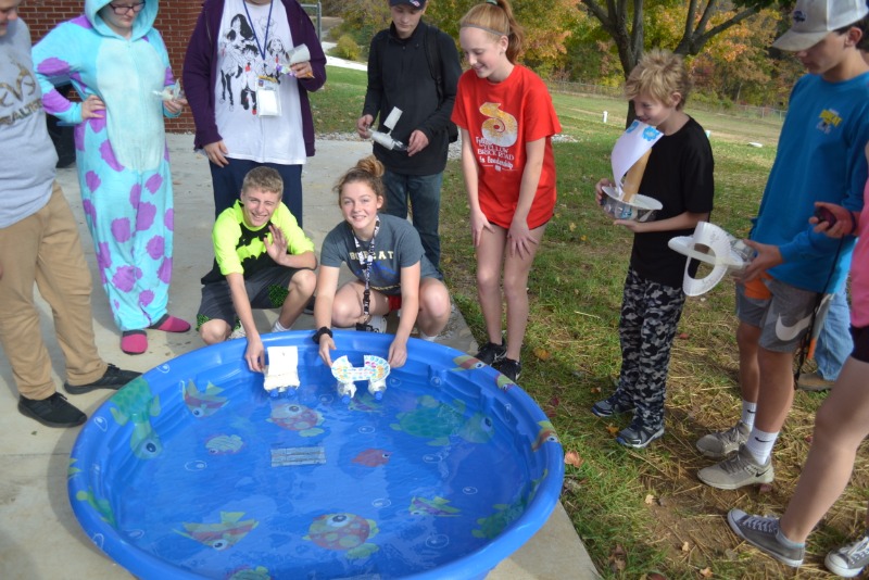 Students racing handmade boats in pool
