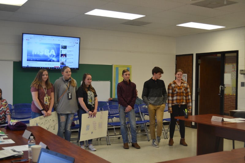 students with posters in front of board