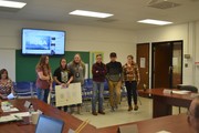 students with posters in front of board