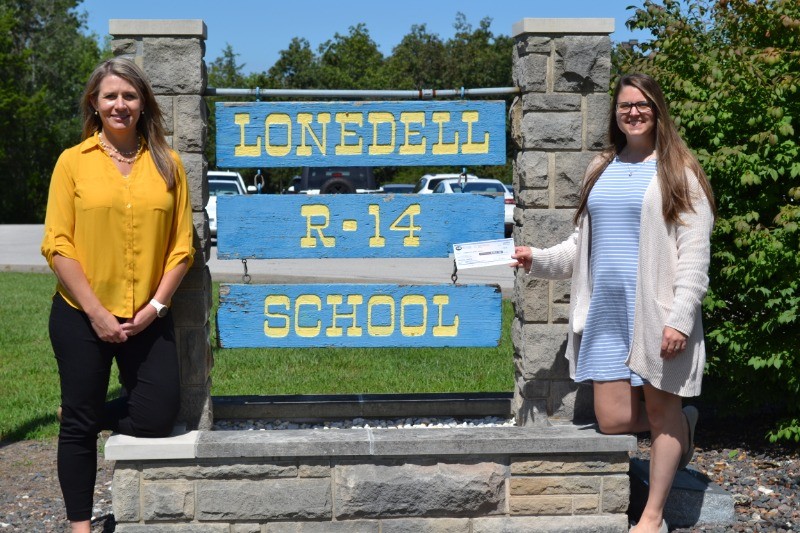 donation check in front of school sign